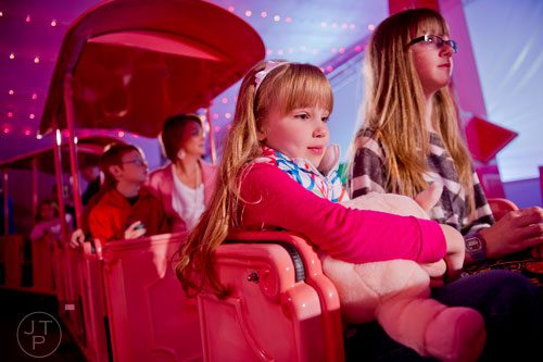 Abby Walton (left) holds onto her stuffed pig as she sits next to her sister Madison while waiting to ride the Macy's Pink Pig at Lenox Square Mall in Buckhead on Saturday, November 2, 2013. 