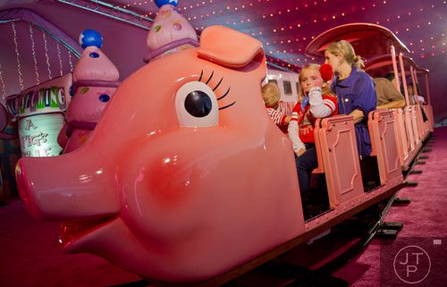 Olivia Dodd (center), Lane Moore (left) and his mother Louise ride the Macy's Pink Pig at Lenox Square Mall in Buckhead on Saturday, November 2, 2013. 