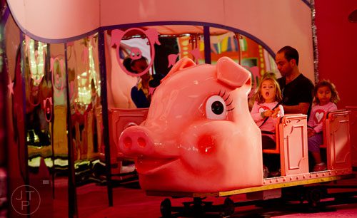 Romy Harari (left) her father Gill and sister Gemma ride the Macy's Pink Pig at Lenox Square Mall in Buckhead on Saturday, November 2, 2013. 