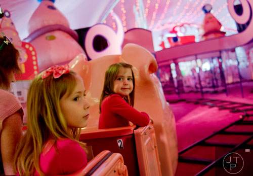 Karina Brooks (right) and her sister Karla ride the Macy's Pink Pig at Lenox Square Mall in Buckhead on Saturday, November 2, 2013. 