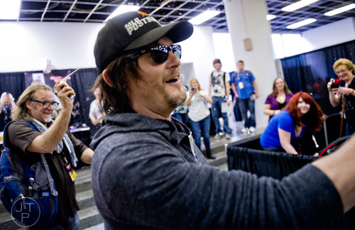 Norman Reedus (center), who plays Daryl on the Walking Dead, and Greg Nicotero, the show's executive producer and special effects makeup designer, spray fans with silly string during Walker Stalker Con at the Atlanta Convention Center at AmericasMart on Saturday, November 2, 2013. 