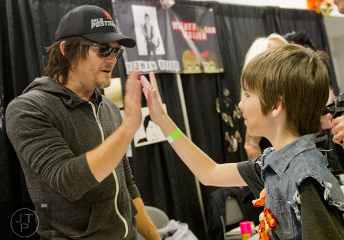 Norman Reedus (left), who plays Daryl on the Walking Dead, gives a high five to Jeremy Joukema during Walker Stalker Con at the Atlanta Convention Center at AmericasMart on Saturday, November 2, 2013. 