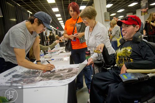 Steven Yeun (left), who plays Glenn on the Walking Dead, signs an autograph for Patti Sargent and her son Len during Walker Stalker Con at the Atlanta Convention Center at AmericasMart on Saturday, November 2, 2013. 