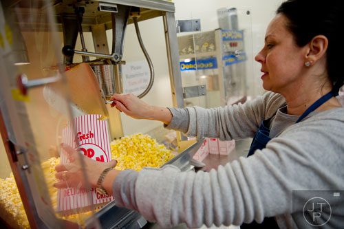 Marist's Tami Keim pours fresh popcorn into a box inside the concession stand before their game against Carver-Atlanta on Friday, November 8, 2013.   
