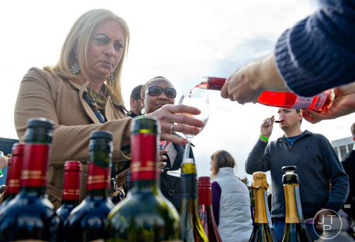 Celeste Rodriguez (left) holds out her glass as wine is poured during the Decatur Wine Festival on Saturday, November 9, 2013. 