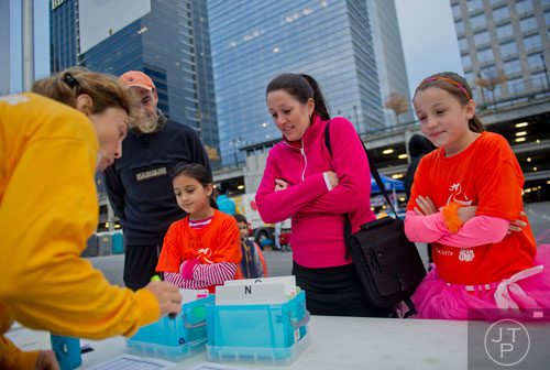Emily Odom (left) and her mother Jennifer and Sacha Sims and her father Andrew talk with Kate Overby as they pick up their race registration before the start of the 2013 Girls on the Run 5k at Atlantic Station in Atlanta on Sunday, November 10, 2013. 