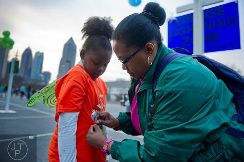 Francine Goodman (right) pins her daughter Basha's bib number on her shirt before the start of the 2013 Girls on the Run 5k at Atlantic Station in Atlanta on Sunday, November 10, 2013. 