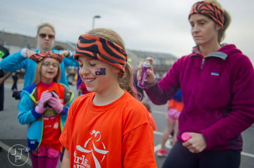 Libby Zufi (center) closes her eyes as her mother Louisa (right) sprays her hair with color as Jennifer Krenson fits a headband on her daughter Grace's head before the start of the 2013 Girls on the Run 5k at Atlantic Station in Atlanta on Sunday, November 10, 2013. 