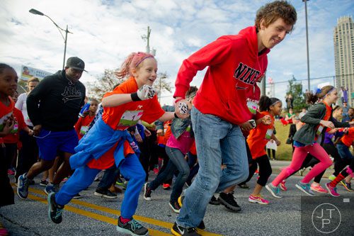 Faith Covey (left) holds hands with her brother Nick as they take off from the starting line during the 2013 Girls on the Run 5k at Atlantic Station in Atlanta on Sunday, November 10, 2013. 
