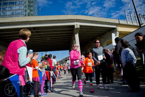 Rebecca Brodnax (left), her daughter Lily and husband Lewis hold hands as they cross the finish line for the 2013 Girls on the Run 5k at Atlantic Station in Atlanta on Sunday, November 10, 2013. 
