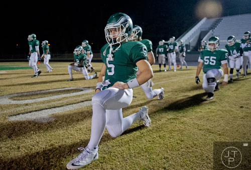 Collins Hill's Tyler Henderson (5) stretches with his teammates before the start of their game against Walton on Friday, November 15, 2013.  