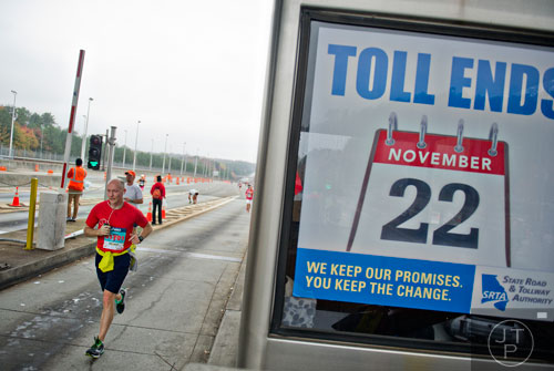David Zaparanick runs through the toll booth on 400 during the GA 400 Pay the Last Toll Race in Atlanta on Sunday, November 17, 2013. 