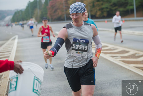 Rivers Ludden reaches out to drop money into a collection bucket at the toll booth on 400 during the GA 400 Pay the Last Toll Race in Atlanta on Sunday, November 17, 2013. 
