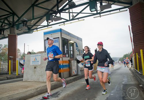 Larry Simons (left), his daughter Erin and Michelle Musser run through the toll booth on 400 during the GA 400 Pay the Last Toll Race in Atlanta on Sunday, November 17, 2013. 