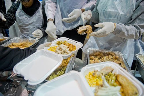 Carrie Mutombo (center) places pieces of meat onto trays during the Hosea Feed the Hungry and Homeless annual Thanksgiving meal at the Georgia World Congress Center in Atlanta on Thursday, November 28, 2013. 