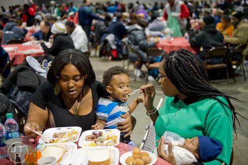 Jonaua Hodge (right) holds her son Malachi as she feeds Javion Flowers while her sister Jacquee Hodge eats a five course Thanksgiving meal during the Hosea Feed the Hungry and Homeless annual Thanksgiving meal at the Georgia World Congress Center in Atlanta on Thursday, November 28, 2013. 