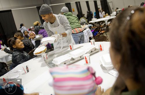 Willie Grant (center), one of hundreds of volunteers, hands a tray of food to Lakayla Shade during the Hosea Feed the Hungry and Homeless annual Thanksgiving meal at the Georgia World Congress Center in Atlanta on Thursday, November 28, 2013.