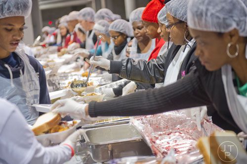 Janet Jack (right), one of hundreds of volunteers, pours gravy on a tray of food during the Hosea Feed the Hungry and Homeless annual Thanksgiving meal at the Georgia World Congress Center in Atlanta on Thursday, November 28, 2013.