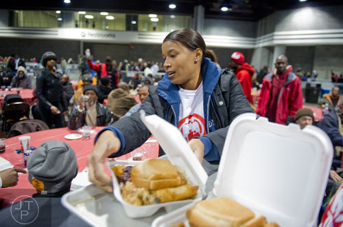Cristina Mullins (center), one of hundreds of volunteers, hands out a tray of food during the Hosea Feed the Hungry and Homeless annual Thanksgiving meal at the Georgia World Congress Center in Atlanta on Thursday, November 28, 2013.