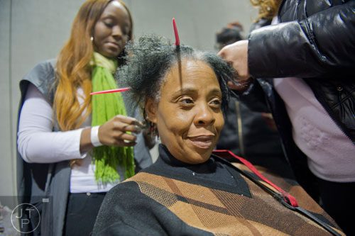 Santina Story (center) gets a haircut from Kirstin Stokes during the Hosea Feed the Hungry and Homeless annual Thanksgiving meal at the Georgia World Congress Center in Atlanta on Thursday, November 28, 2013.