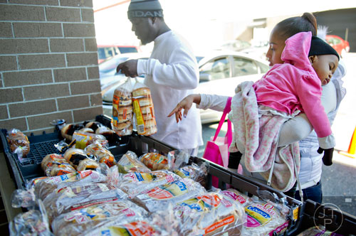 Alicia Desire (right) sleeps on her mother Jessica's shoulder as her father Veiginio picks up loaves of bread at Daily Bread for All in Norcross on Thursday, November 14, 2013. 