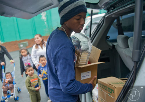 Cole Gilbert (center) carries Thanksgiving supplies to Blanca Castillo's car at the Philip Rush Center in the Edgewood neighborhood of Atlanta on Sunday, November 17, 2013. 
