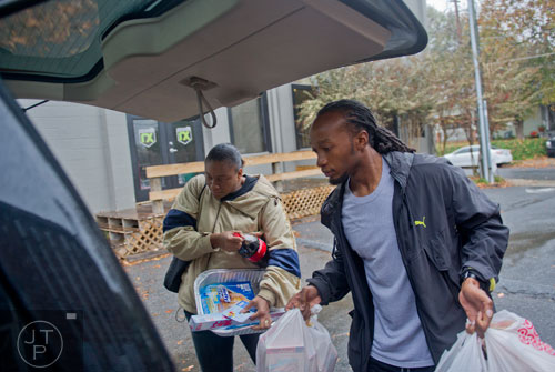 Eric Willie (right) helps April Lewis carry Thanksgiving supplies to her car at the Philip Rush Center in the Edgewood neighborhood of Atlanta on Sunday, November 17, 2013. 