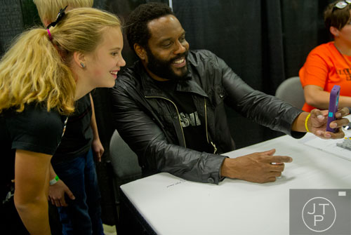 Reina Abernathy (left) smiles as Chad L. Coleman, who plays Tyreese on The Walking Dead, takes a photo of the two of them with her phone during Walker Stalker Con at the Atlanta Convention Center at the AmericasMart on Saturday, November 2, 2013.