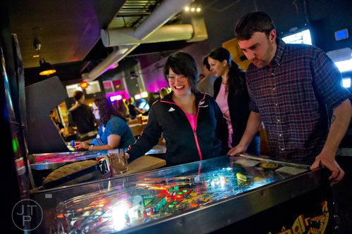 Linda Eller (left) smiles as she watches Adam Shumaker play a game of pinball  at Joystick Game Bar in the Old Fourth Ward neighborhood of Atlanta on Saturday, November 2, 2013.