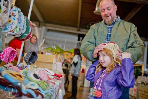 Charlee Thrice (right) tries on a hand made hat with help from her father Eric at the LylahG booth during the Indie Craft Experience at Ambient Plus Studio in Atlanta on Saturday, November 23, 2013. 