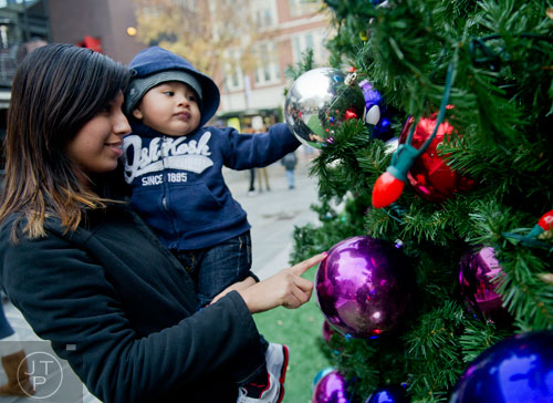 Montserrat Adame (left) holds her son Ian Espinoza as they touch the ornaments on the tree at Atlantic Station in Atlanta during the annual Christmas tree lighting as thousands of people watch the show on Saturday, November 23, 2013.