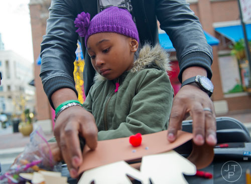 Taylor Dease puts the finishing touches on her reindeer hat as her father Mike holds it on the table at Atlantic Station in Atlanta during the annual Christmas tree lighting as thousands of people watch the show on Saturday, November 23, 2013. 