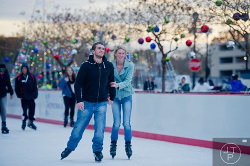 Anthony Keith (left) holds hands with Hannah Shuler as they ice skate at Atlantic Station in Atlanta during the annual Christmas tree lighting as thousands of people watch the show on Saturday, November 23, 2013. 