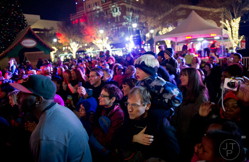 Erik Speakman (center) holds his son Alexander on his shoulders as they watch one of the live performances at Atlantic Station in Atlanta during the annual Christmas tree lighting on Saturday, November 23, 2013. 