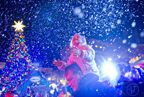 Don Johnson (left) holds his daughter Tyler on his shoulders as snow falls at Atlantic Station in Atlanta during the annual Christmas tree lighting on Saturday, November 23, 2013. 