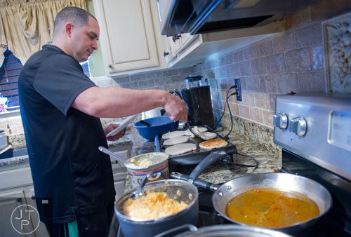 Pablo Borrero cooks breakfast for his wife and five children at their home in Dacula on Sunday, November 24, 2013. 