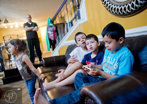 Ethan Borrero (right), his brothers Pablo Jr. and Nathan and sister Autumn play in the living room as their father Pablo watches from the kitchen at their home in Dacula on Sunday, November 24, 2013. 