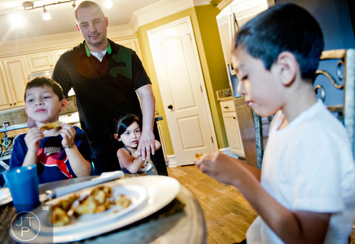 Pablo Borrero (center) stands in his kitchen with his arm around his daughter Autumn as two of his sons Pablo Jr. (left) and Nathan eat breakfast at their home in Dacula on Sunday, November 24, 2013.