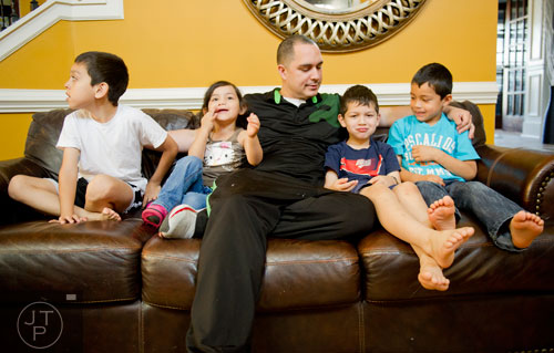 Pablo Borrero (center) sits on the couch with four of his children, Nathan (left), Autumn, Pablo Jr. and Ethan at their home in Dacula on Sunday, November 24, 2013. 