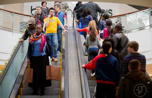 Urike Brown (left) rides the escalator as she carries shopping bags at Lenox Square Mall in Atlanta on Friday, November 29, 2013. 