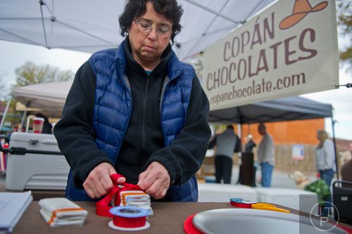 Sharon Valery ties a red ribbon around a stack of chocolate bars at the Copan Chocolates booth at the farmers market in Marietta Square on Saturday, November 9, 2013. 