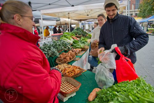 Daniel Continenza (right) puts his carrots away as he talks with Belinda Wernau (left) while Greta Herbert waits to pay for her purchases at the farmers market in Marietta Square on Saturday, November 9, 2013.    