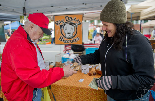 Lauren Janis (right) hands Dick Lamborn his packages of dog treats at the Big Daddy Biscuits booth at the farmers market in Marietta Square on Saturday, November 9, 2013. 