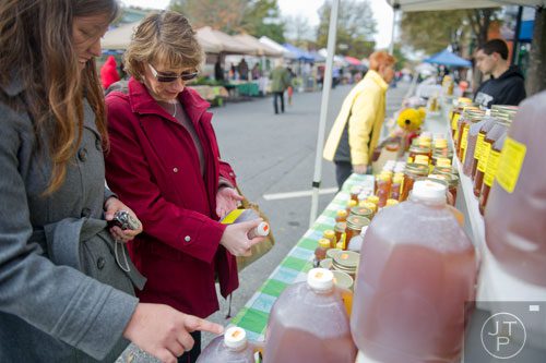 Monica Hicks (left) and Sandra Collins look at different containers of honey at the Home Town Honey booth at the farmers market in Marietta Square on Saturday, November 9, 2013. 
