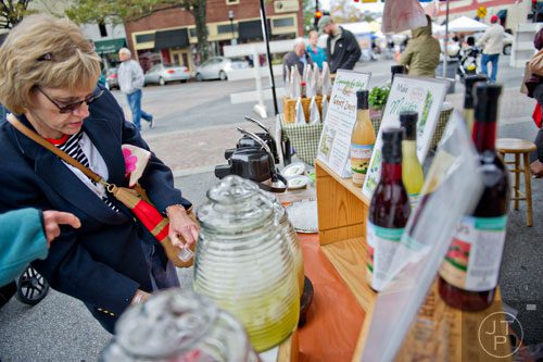 Laurie Bartron (left) tries a sample at the Mo' Mint & Thyme booth at the farmers market in Marietta Square on Saturday, November 9, 2013. 