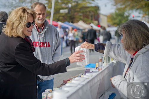 Becki Mudgett (left) reaches for her purchases from Dixie Reaver at The Herb Garden booth at the farmers market in Marietta Square on Saturday, November 9, 2013. 