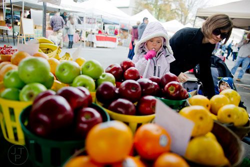 Mia Lisonbee (left), her mother Ashley and brother Andrew look at fresh fruits for sale at the farmers market in Marietta Square on Saturday, November 9, 2013.     