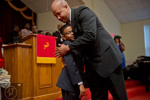Dr. Brian Bolden (right), principal at the Ronald E. McNair Learning Academy, hugs Kyle Chandler Stocks after his family, local businesses and Mt. Welcome Missionary Baptist Church make donations to the school during worship services at the church in Decatur on Sunday, December 8, 2013. 