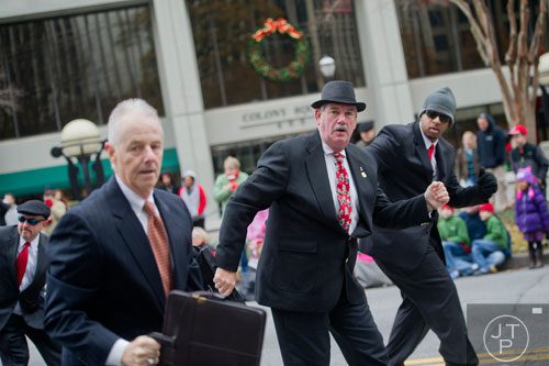 John Sokol (center) dances his way down Peachtree Street with the Briefcase Brigade during the 33rd annual Children's Christmas Parade in Atlanta on Saturday, December 7, 2013. 