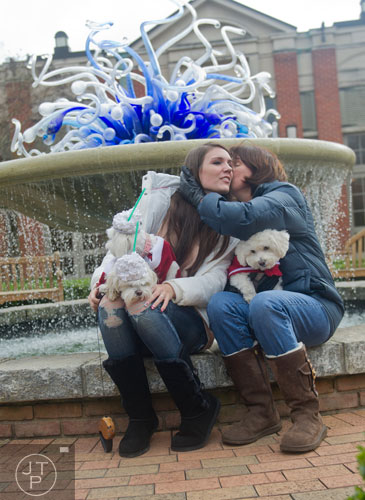 Teresa Williams gives Stella Harney a kiss as they hold their dogs Buddy, Buffy and Outfit at the Atlanta Botanical Garden on Saturday, December 7, 2013.